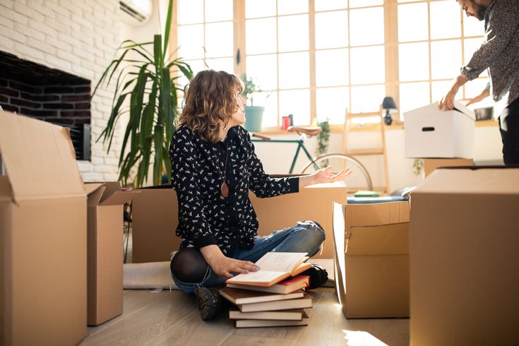 this picture contains a woman seating on the floor and big boxes by the sides